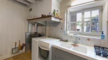 A kitchen with a built-in oven, a sink, and a window with a view of greenery.
