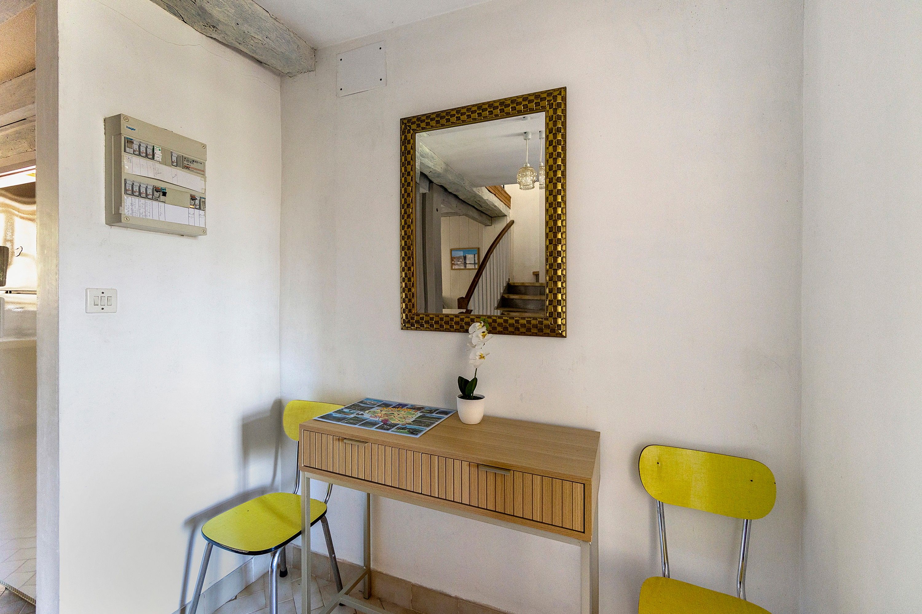 Una habitación con un escritorio de madera, un espejo, un mapa y dos sillas amarillas.