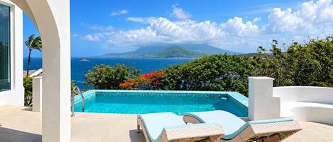 A swimming pool with a view of the ocean and a mountain in the background.