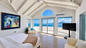 A bedroom with a bed, a TV, a chair, and a painting.