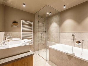 A modern bathroom with a glass-enclosed shower, a large bathtub, and a vanity with a mirror. - Apartment in Schruns With Swimming Pool (Schruns)