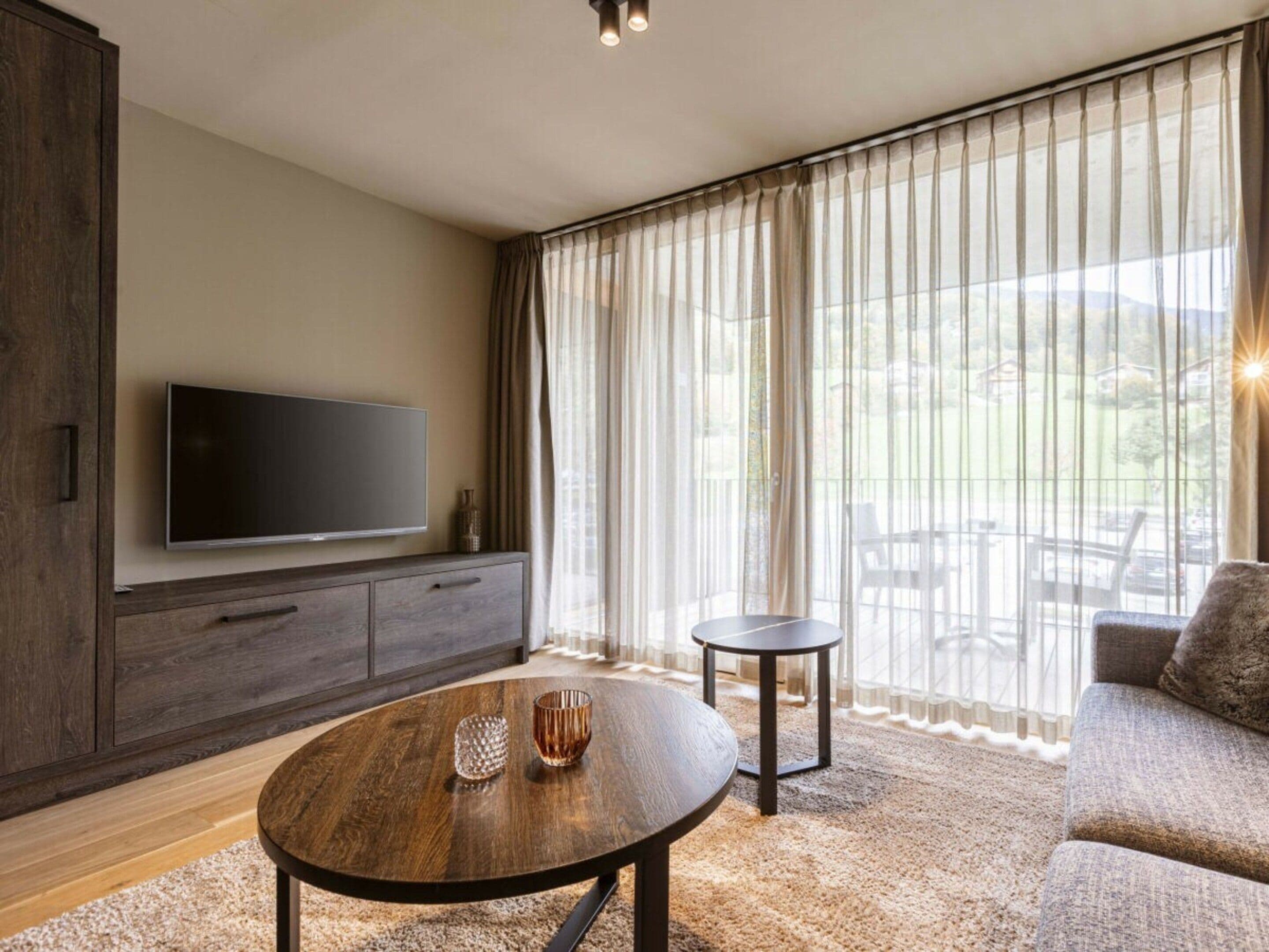 A modern living room with a flat-screen TV, a round coffee table, and a sofa.