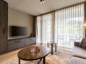 Ein modernes Wohnzimmer mit Flachbildfernseher, rundem Couchtisch und einer Couch.