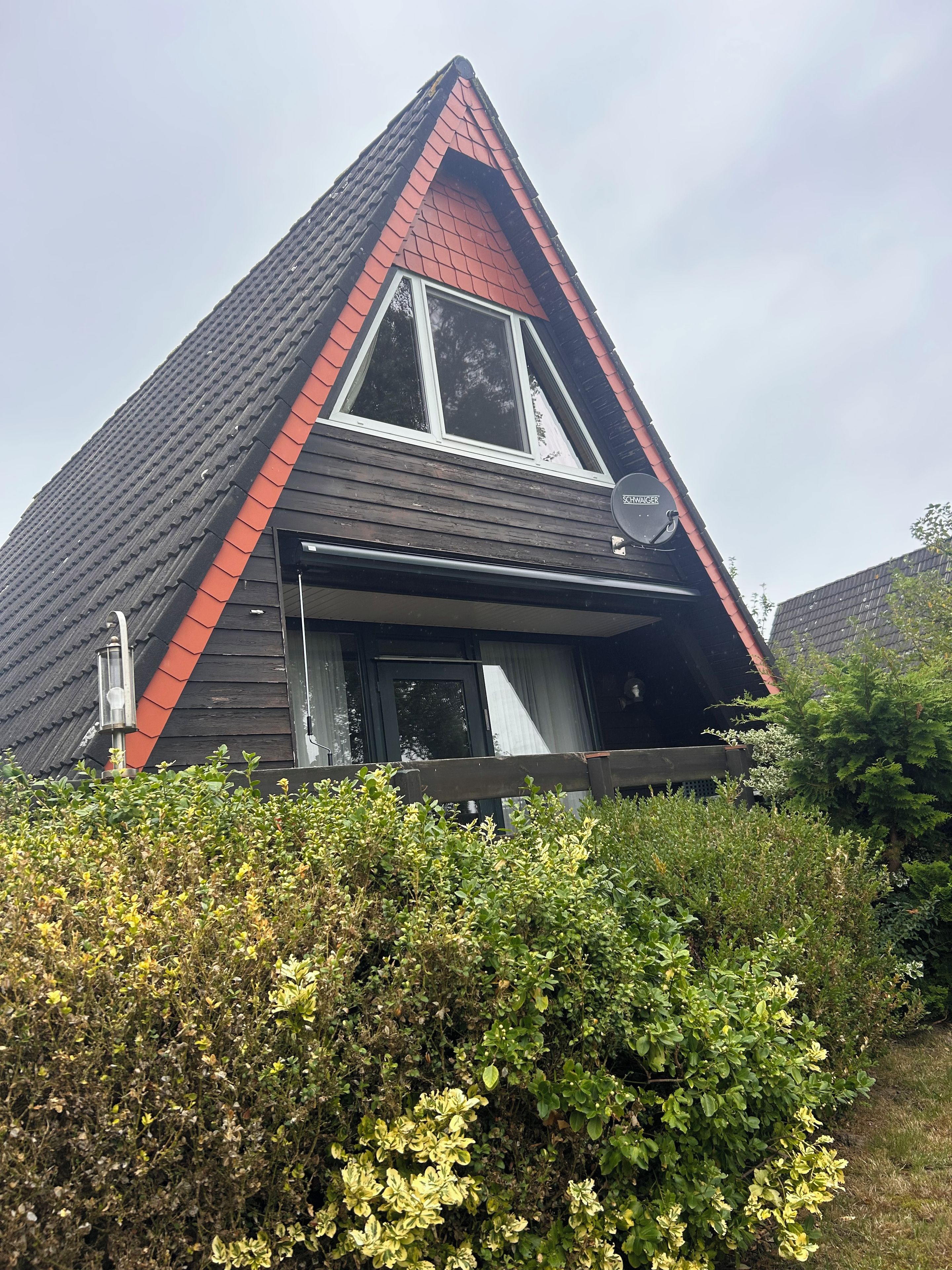 Een huis met een schuin dak, een schotelantenne en een raam.
