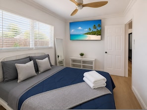 A bedroom with a bed, a ceiling fan, a TV on the wall, and a door to another room. - Sunset Paradaise in Fort Lauderdale (Fort Lauderdale)