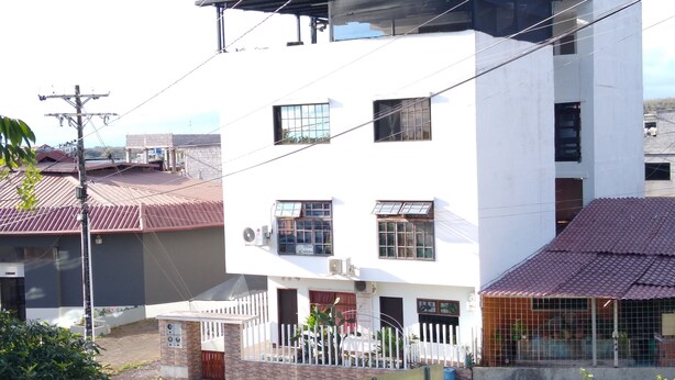 A multi-story building with a flat roof, a fenced yard, and a paved street. - CASA RENTERA D'ELIAS (San Cristóbal)