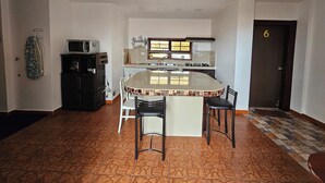 A kitchen with a central island, white walls, and a tiled floor. - CASA RENTERA D'ELIAS (San Cristóbal)