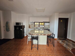 A kitchen with a central island, white walls, and a tiled floor. - CASA RENTERA D'ELIAS (San Cristóbal)