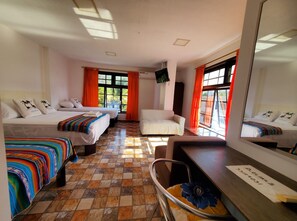 A hotel room with two beds, a sofa, a chair, a desk, and a large mirror. - CASA RENTERA D'ELIAS (San Cristóbal)
