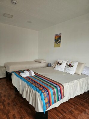 Una habitación con dos camas, una manta colorida y un cuadro en la pared.