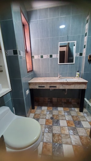 Ein Badezimmer mit Marmorwaschbecken, einem Spiegel und einer Toilette.