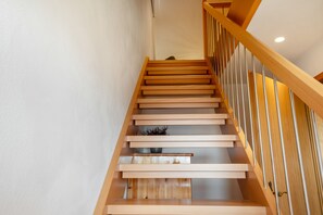Un escalier en bois, doté d’une rampe et d’un luminaire en haut.