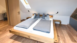 Quarto com cama de madeira, claraboia, guarda-roupa e uma pequena mesa de cabeceira.
