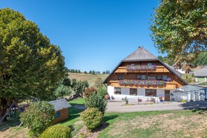 Un bâtiment à deux étages, doté d’un toit en pente, d’une façade en bois et de jardinières sur les balcons.