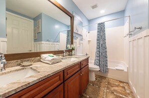 Ein Badezimmer mit Marmorwaschtisch, einer Dusche mit blauer Duschvorhang und einer Toilette.