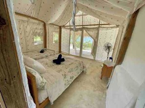 A bedroom with a canopy bed, a bedside table, and a window.