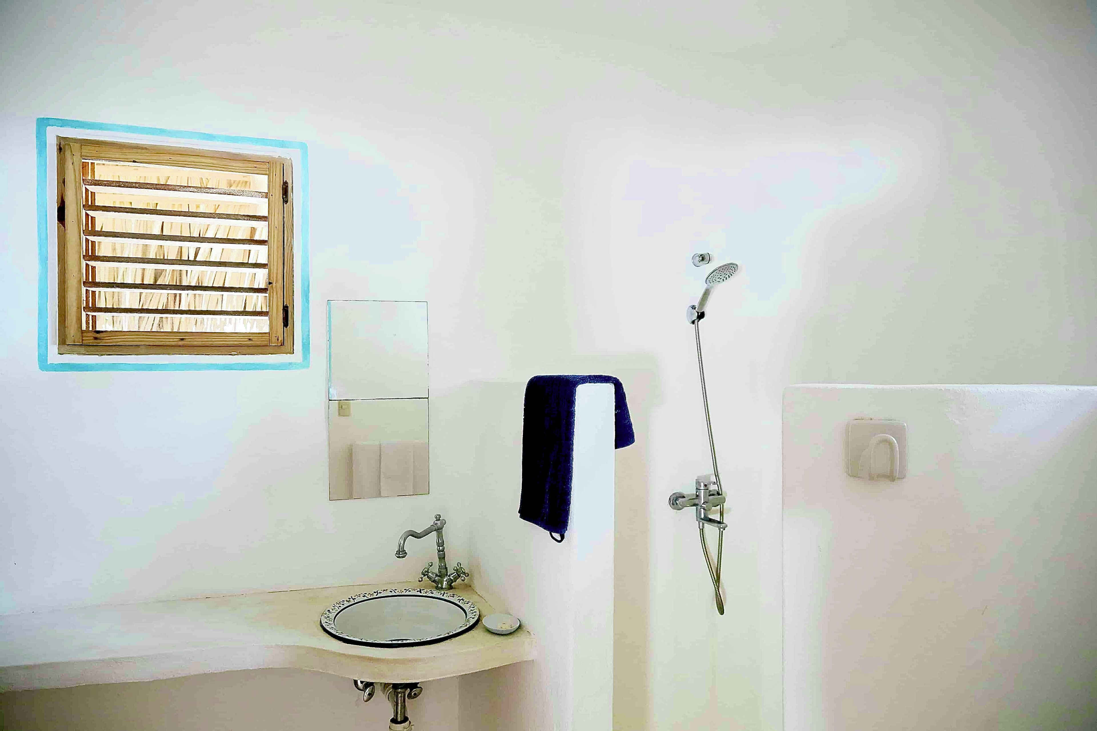 A bathroom with a sink, mirror, towel rack, and shower.