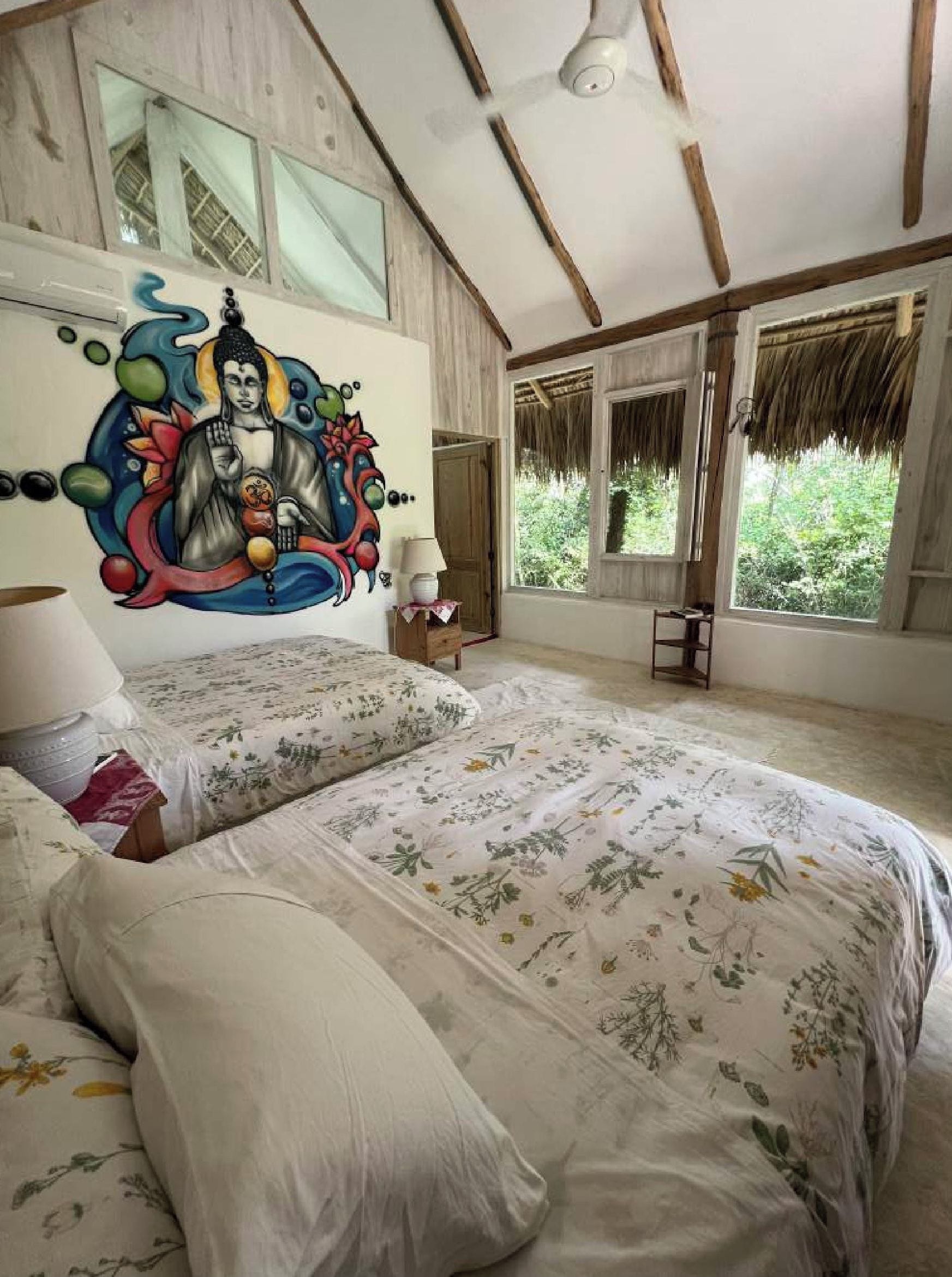 Un dormitorio con una cama grande, un mural en la pared y vistas a zonas verdes.