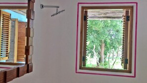 Una habitación con ventana, puerta de madera y una lámpara fijada a la pared.