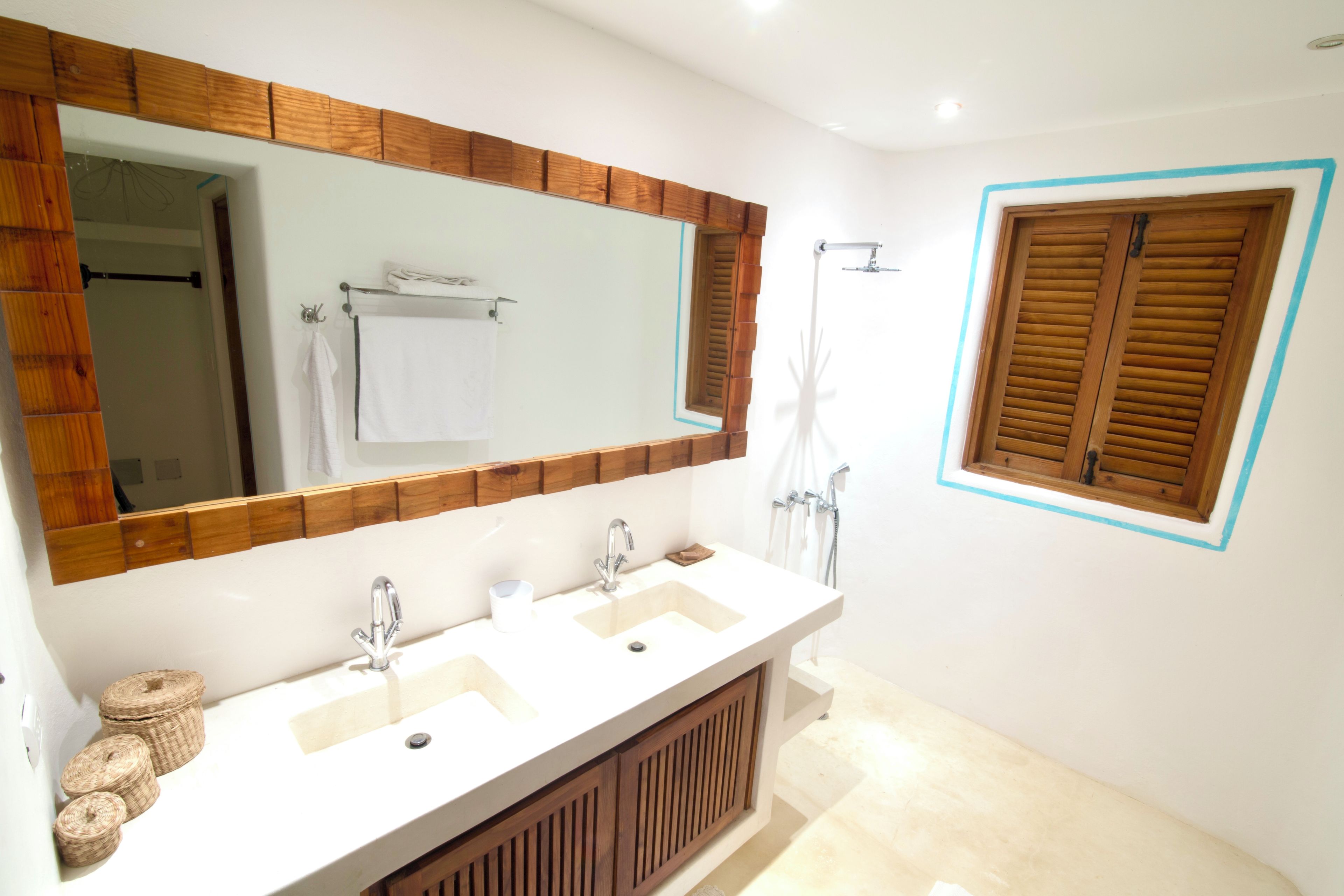Une salle de bain avec un grand miroir, deux lavabos, une douche et un lambris en bois.
