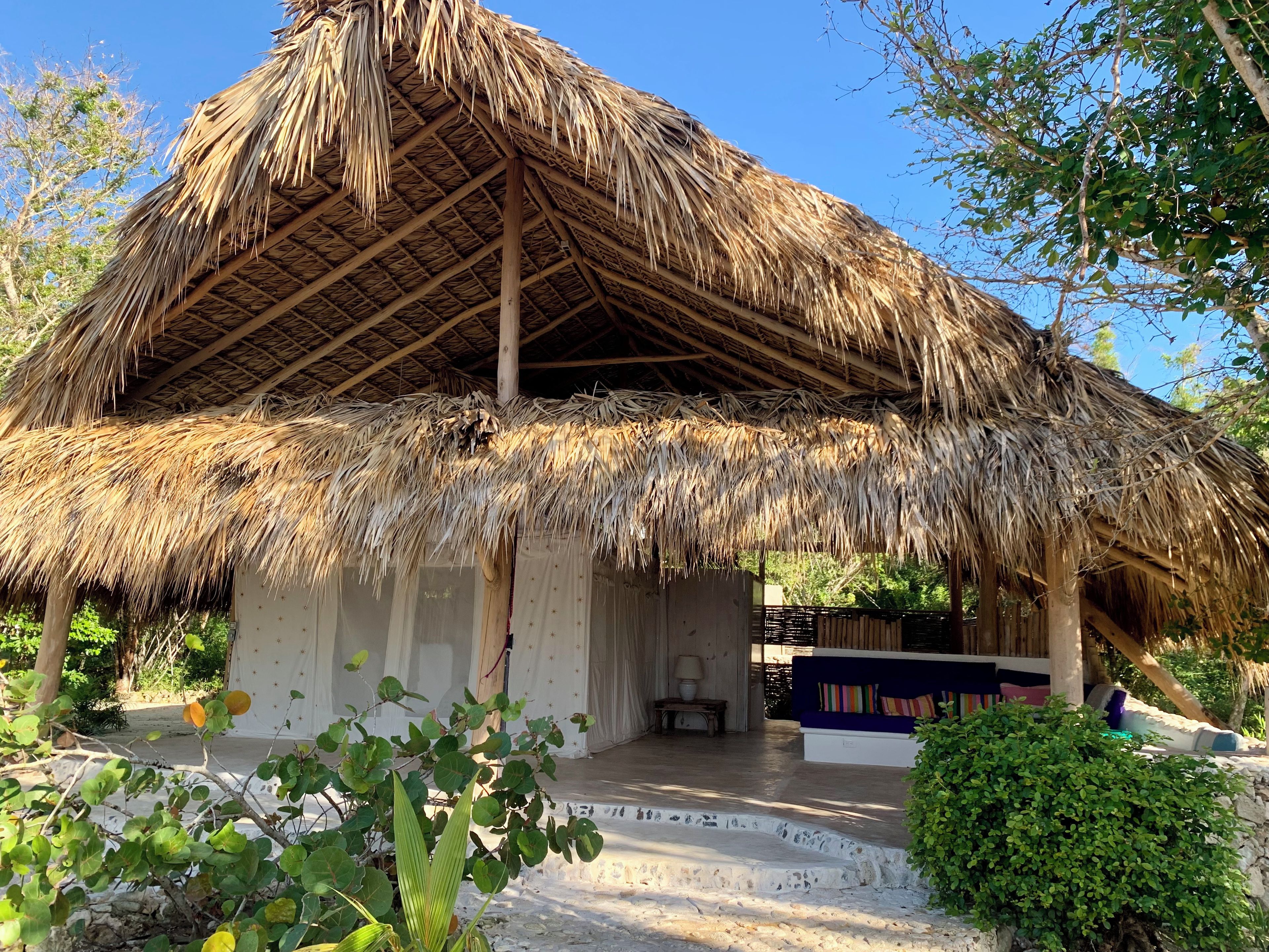 A thatched-roof structure with a porch and seating area.