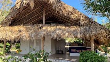 A thatched-roof structure with a porch and seating area.