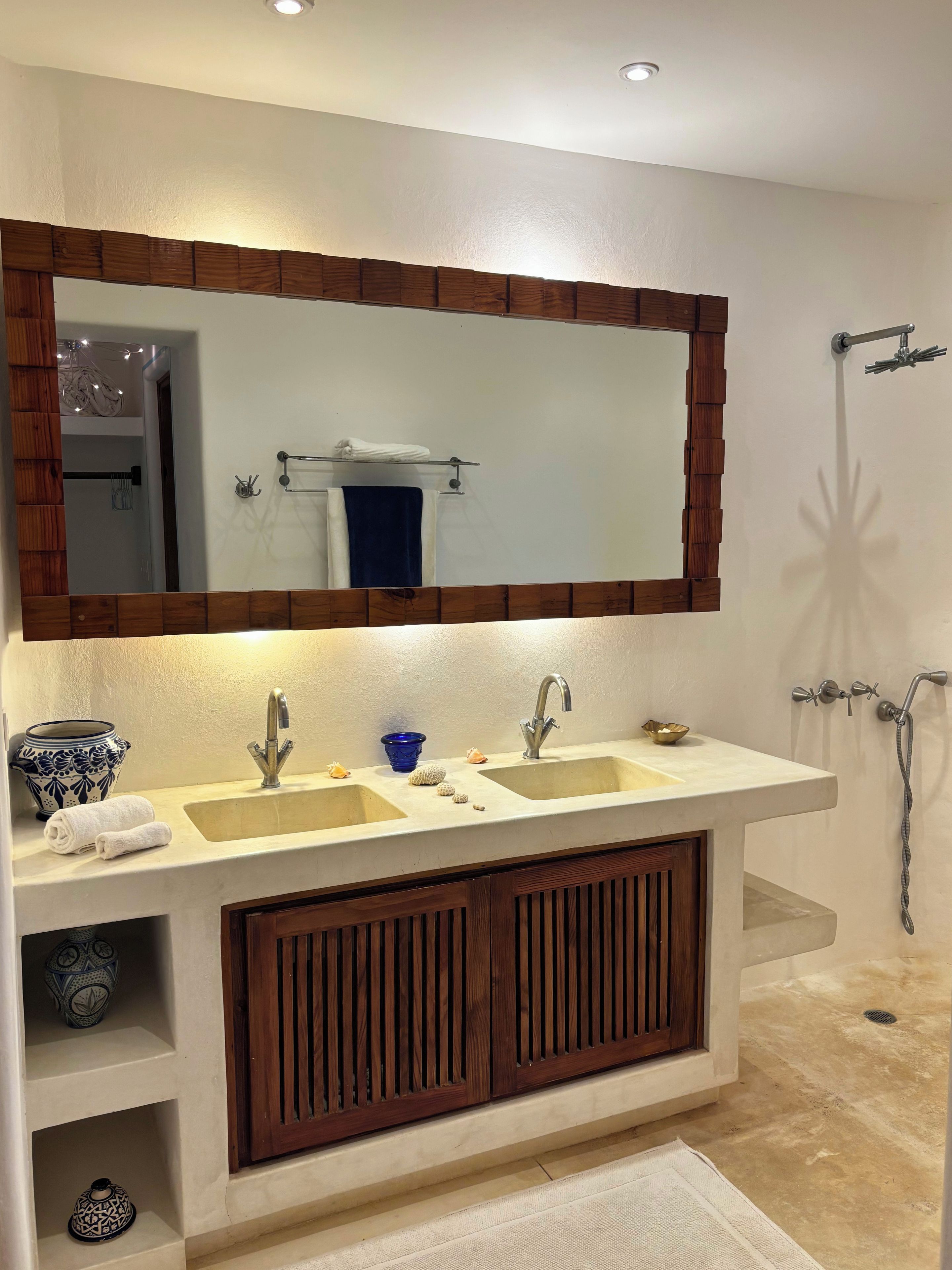 A bathroom with a double sink vanity, a large mirror, and a shower area.