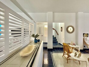 Ein modernes Interieur mit einer langen Diele, einer Treppe und einer Sitzecke mit Tisch und Stühlen.