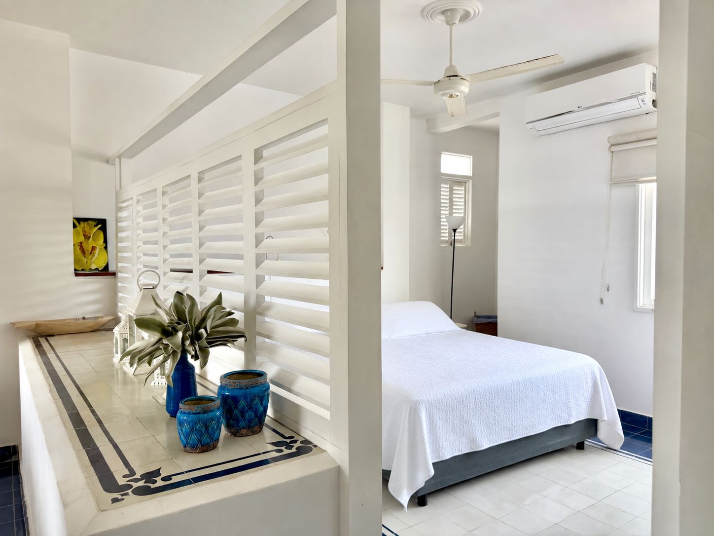 Un dormitorio con cama, ventilador de techo y unidad de aire acondicionado.