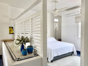 Ein Schlafzimmer mit einem Bett, einem Deckenventilator und einer Klimaanlage.