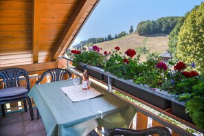 Ein Balkon mit Tisch für zwei Personen, der auf eine reizvolle Landschaft blickt.