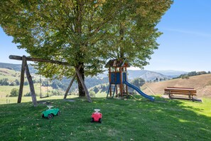 A playground with a slide and swings, set against a backdrop of hills and a clear sky. - Apartment 'Ferienwohnung Waldzauber' with Mountain View, Shared Terrace and Wi-Fi (Münstertal/Schwarzwald)