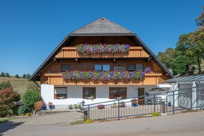 A two-story building with a wooden facade, a balcony with flower boxes, and a visible ground floor entrance. - Apartment 'Ferienwohnung Waldzauber' with Mountain View, Shared Terrace and Wi-Fi (Münstertal/Schwarzwald)