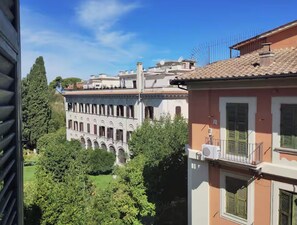A courtyard with a building featuring arched windows and a tiled roof. - La Dimora Torlonia Elegance & Light in Rome (Roma)