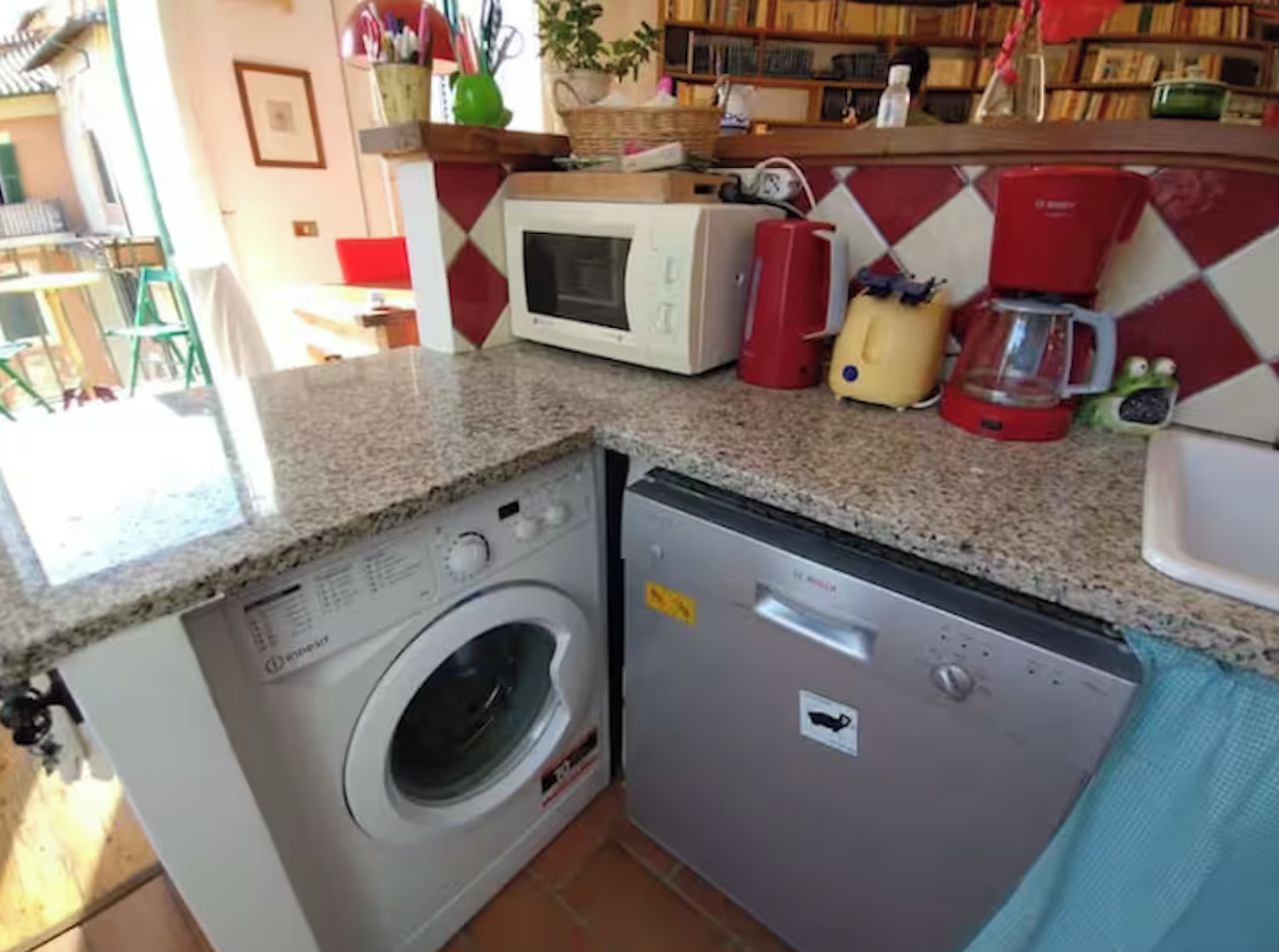 Une cuisine compacte équipée d’un lave-linge, d’un four à micro-ondes et d’une machine à café.