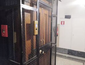 A metal security gate with a lock and a red emergency exit sign on the wall. - La Dimora Torlonia Elegance & Light in Rome (Roma)