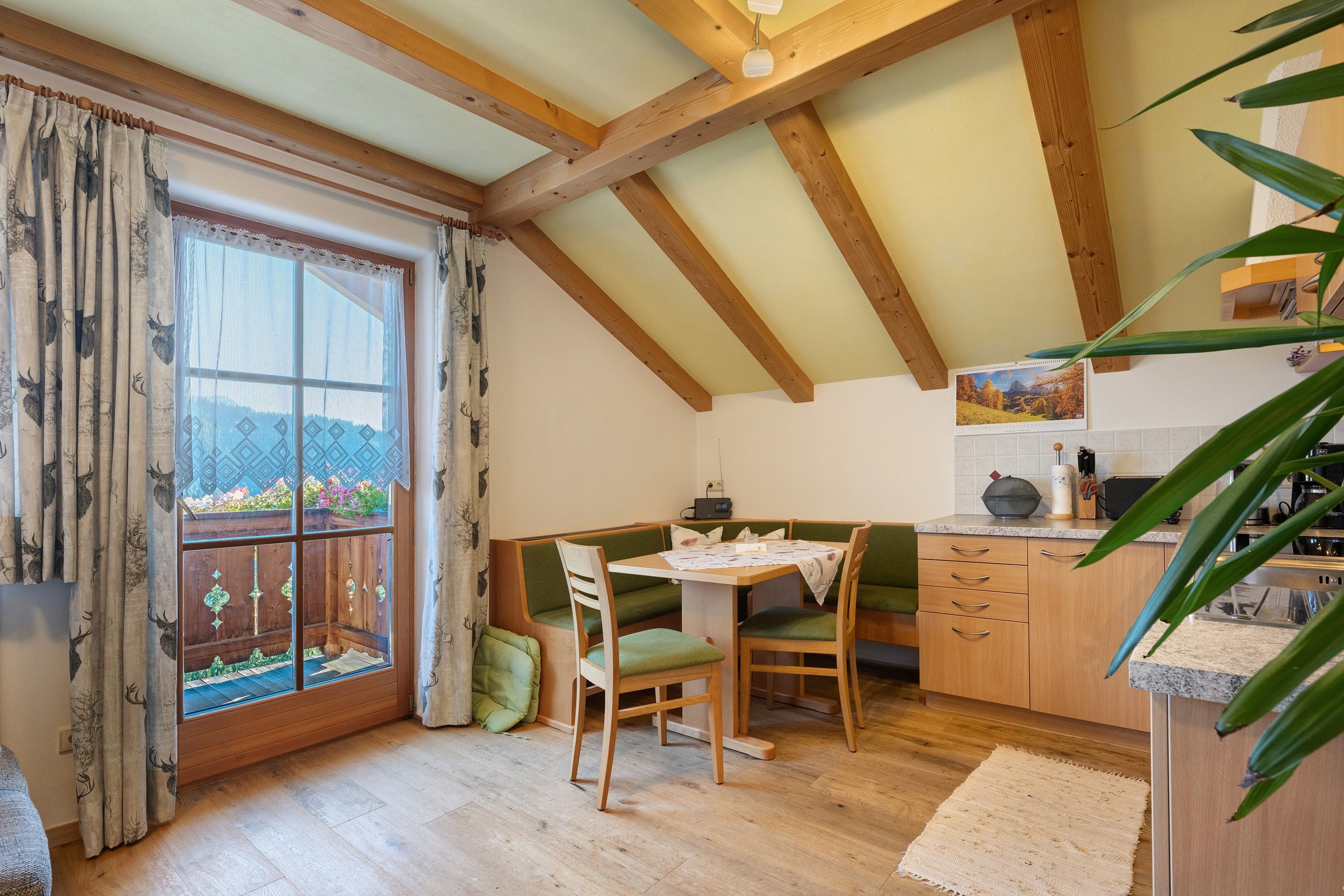 Ein gemütlicher Essbereich mit Holztisch, Stühlen und Blick durch ein mit Vorhängen drapiertes Fenster.
