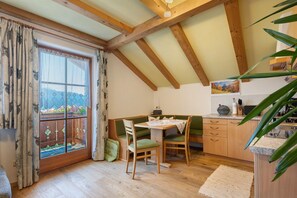 Un rincón comedor acogedor con una mesa de madera, sillas y vistas a través de una ventana con cortinas.