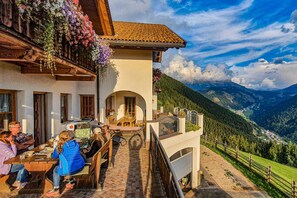 Un edificio con terraza, mobiliario exterior y vistas a la montaña.