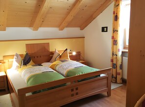 Una cama de madera con cabecera, dos mesitas de noche y una lámpara.
