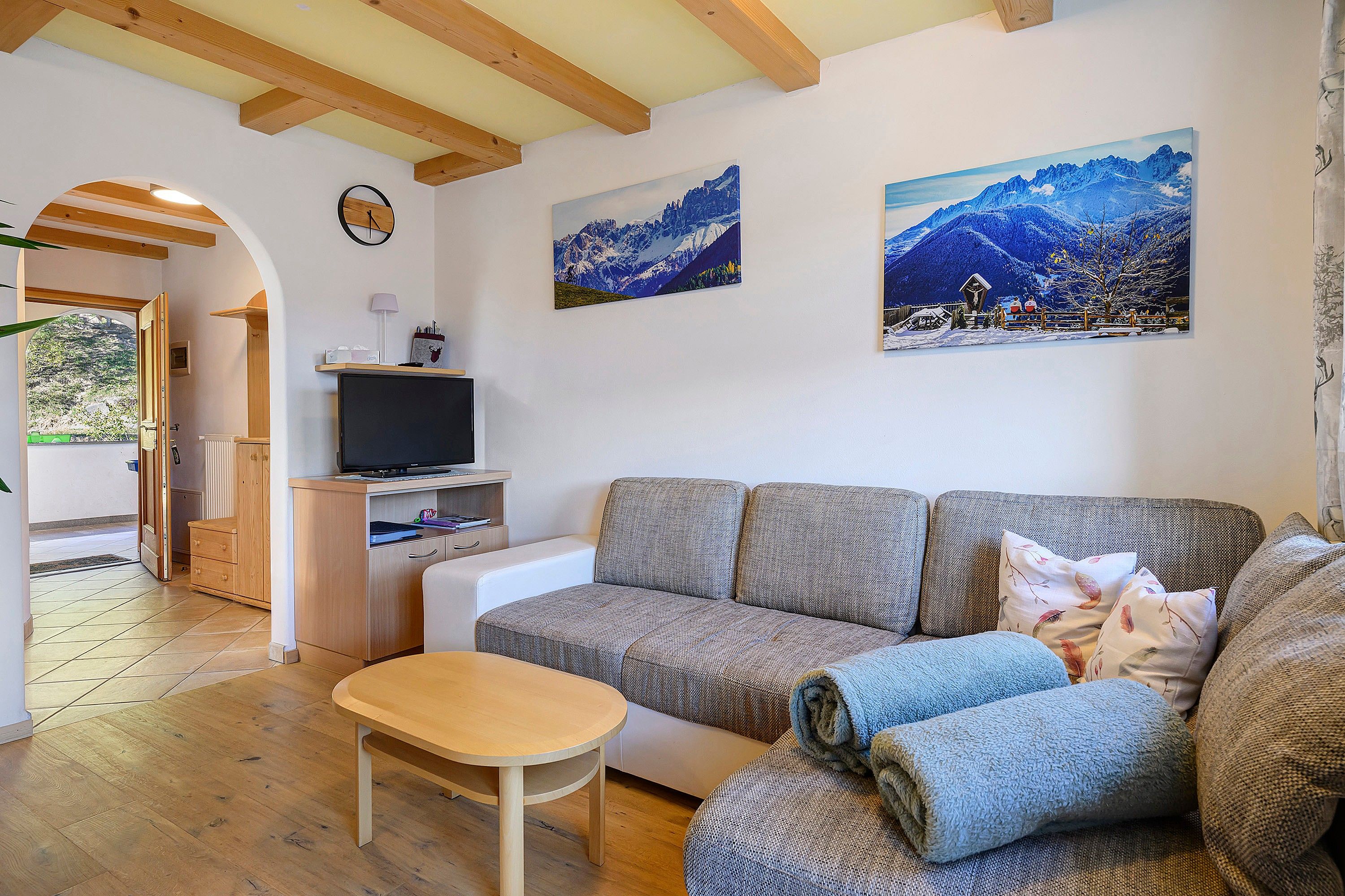 A living room with a sofa, a TV, and paintings on the wall.
