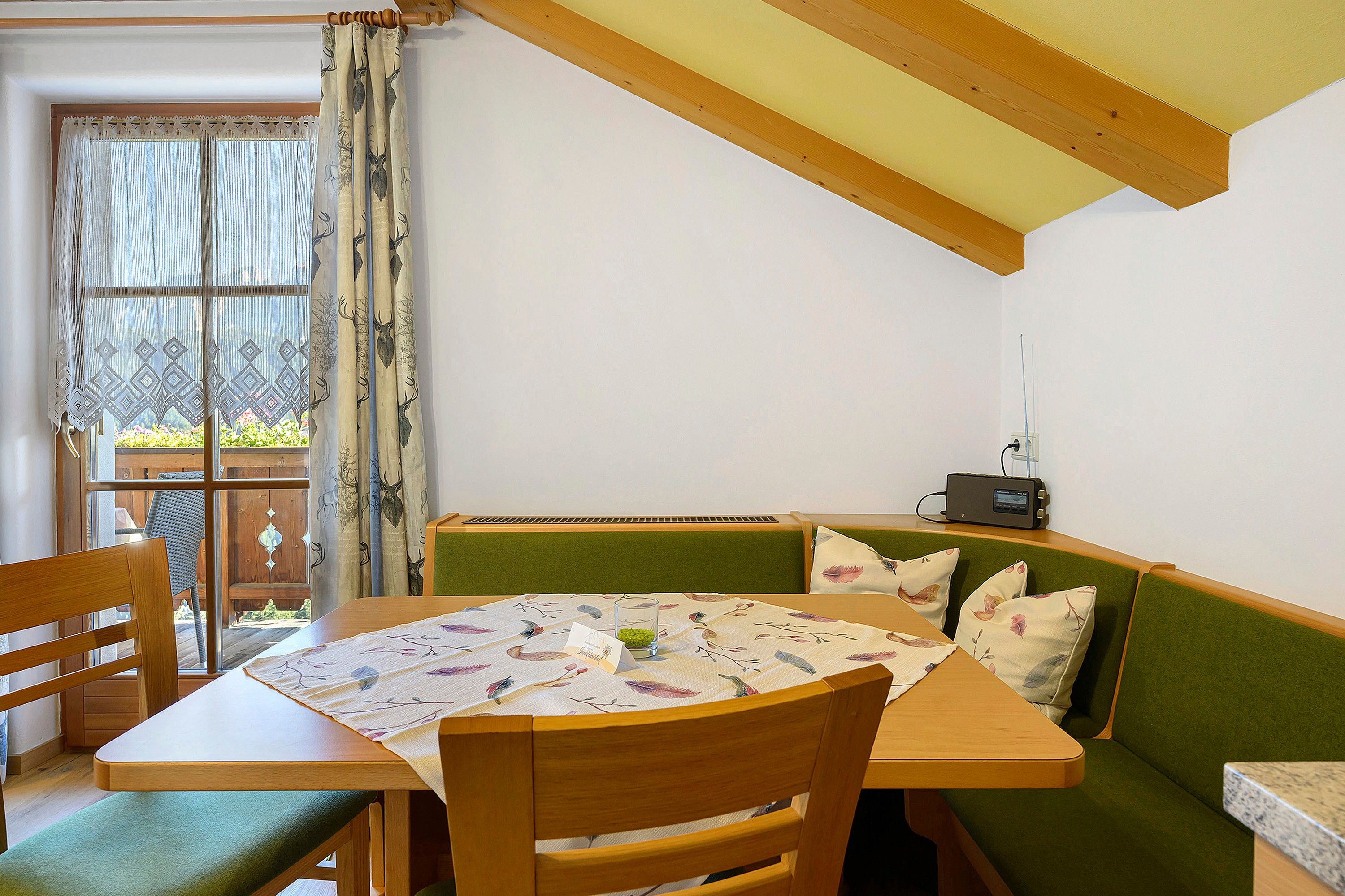 Un coin repas accueillant avec une table en bois, des chaises et un banc vert rembourré.