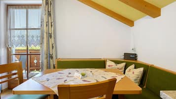Un coin repas accueillant avec une table en bois, des chaises et un banc vert rembourré.