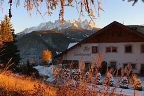 Un albergue de montaña con un letrero que dice 'Innfocherhof' y una vista de montañas nevadas al fondo.