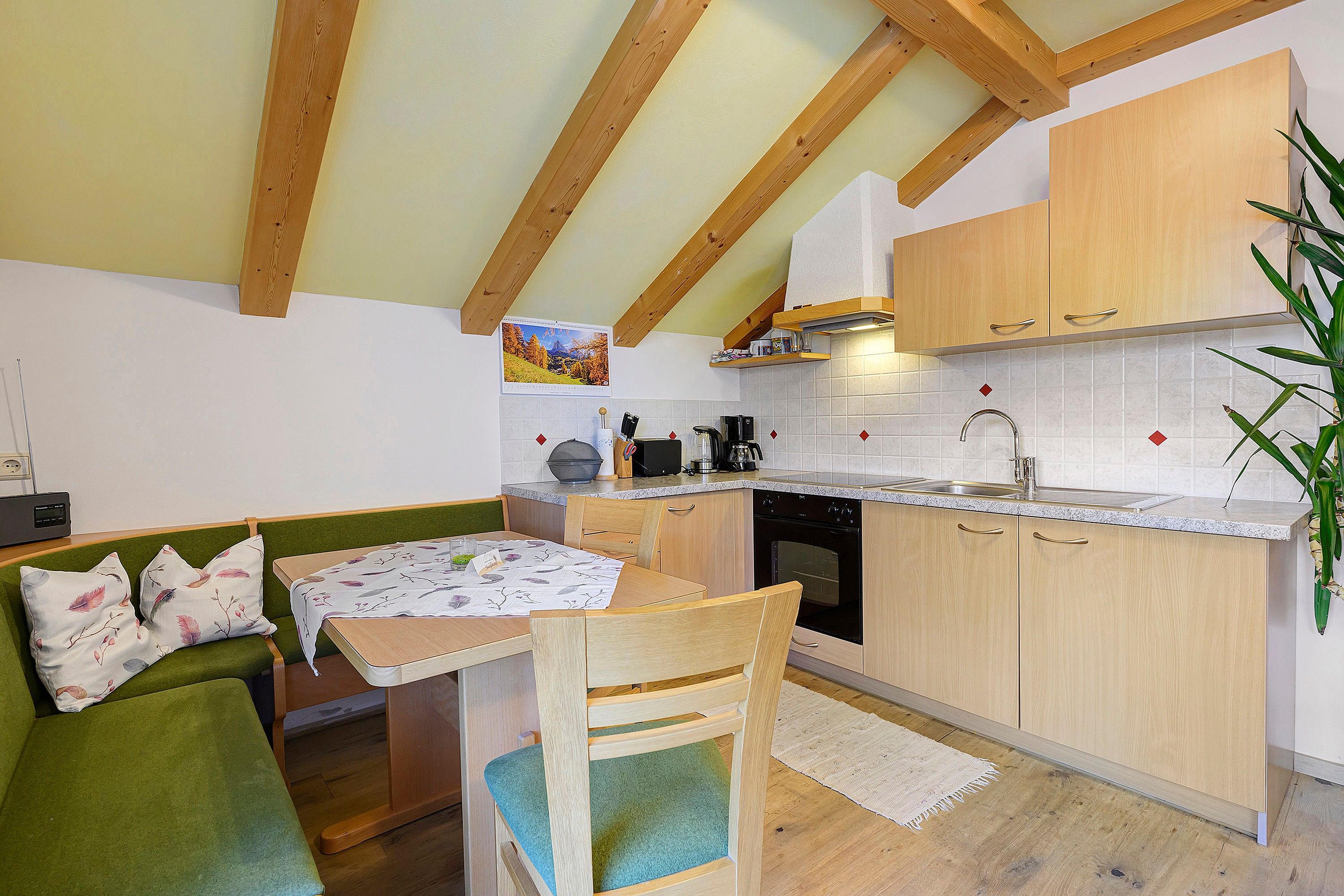 A compact kitchen with wooden cabinets, a dining table with chairs, and a built-in oven.