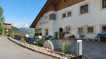 Il s’agit d’un bâtiment alpin traditionnel offrant une vue sur la montagne, avec des poutres en bois et une enseigne indiquant la présence d’un restaurant.