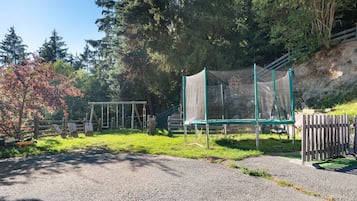 Une aire de jeux avec un trampoline, des balançoires et une structure d’escalade.