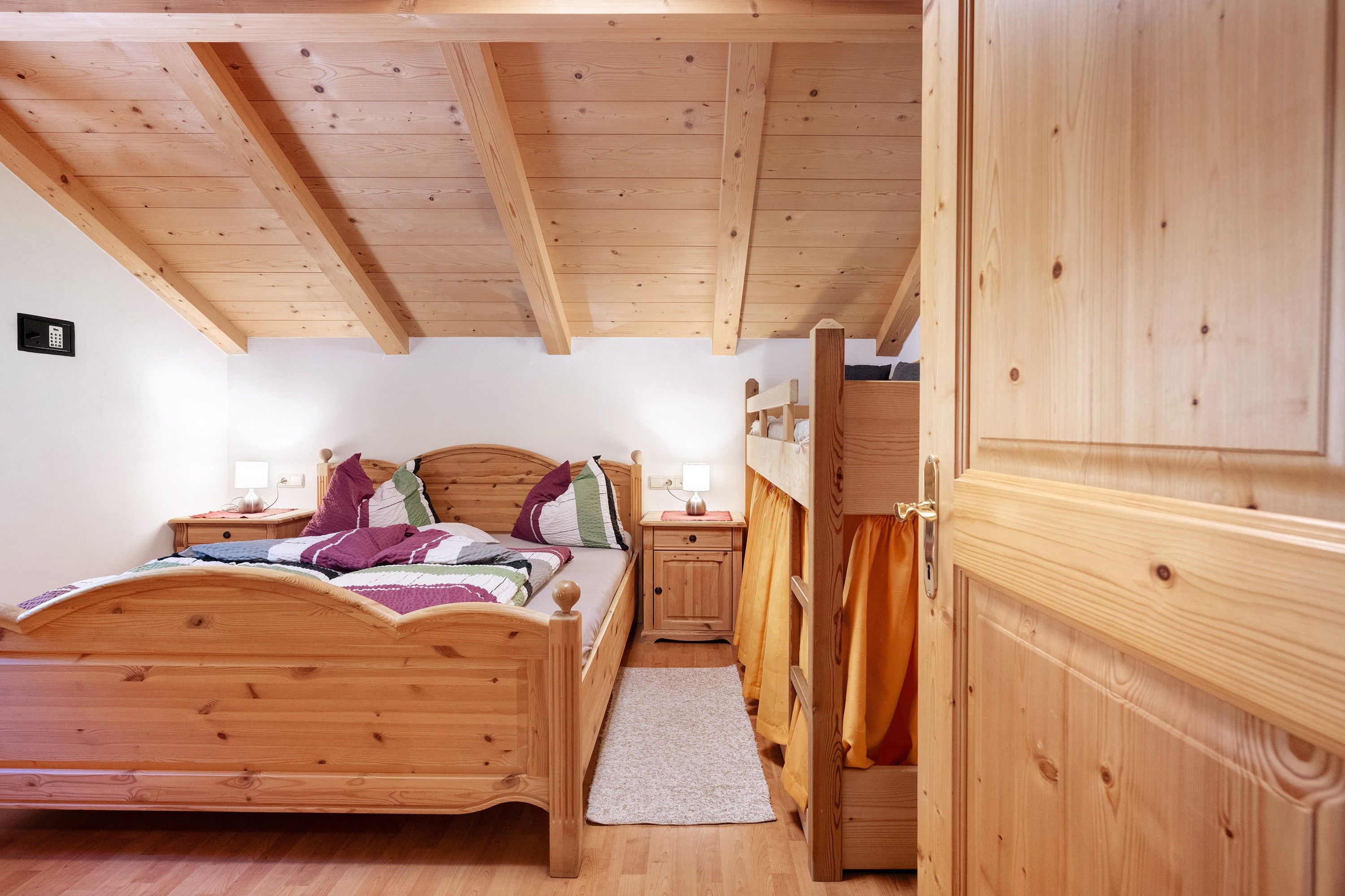 Une chambre à coucher en bois, avec un lit, des tables de chevet, une commode, une armoire et une porte.