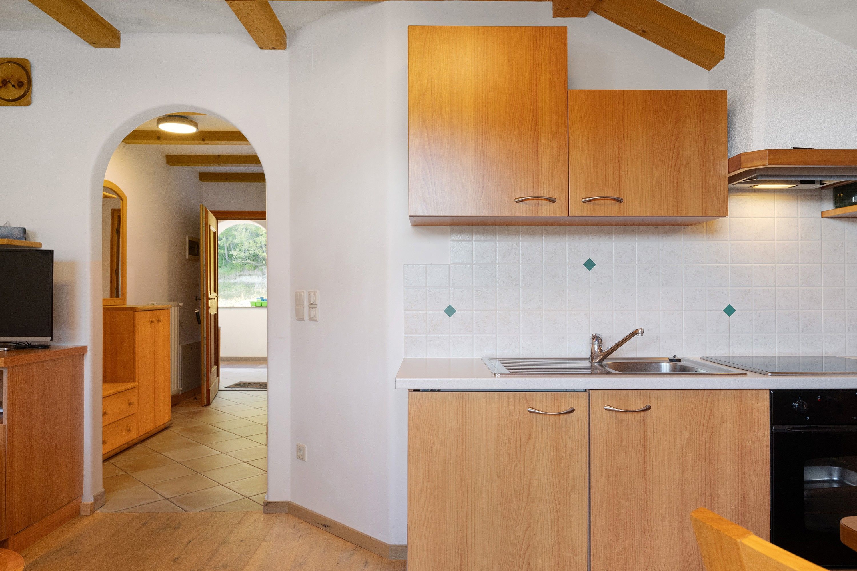A kitchen with wooden cabinets, a sink, and a stove.