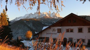 Et fjeldhotel med et skilt, der siger 'Innfocherhof', og udsigt til bjerge med sne.